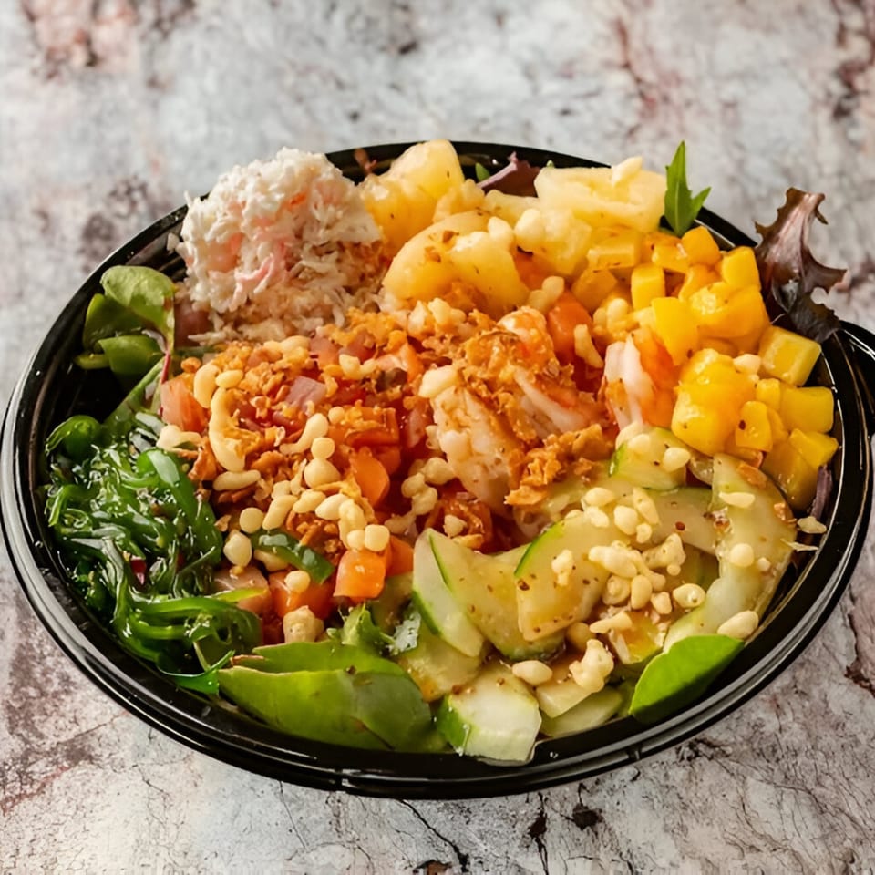 A vibrant PokeCity poke bowl with shrimp, crab, pineapple, mango, seaweed, and cucumber.