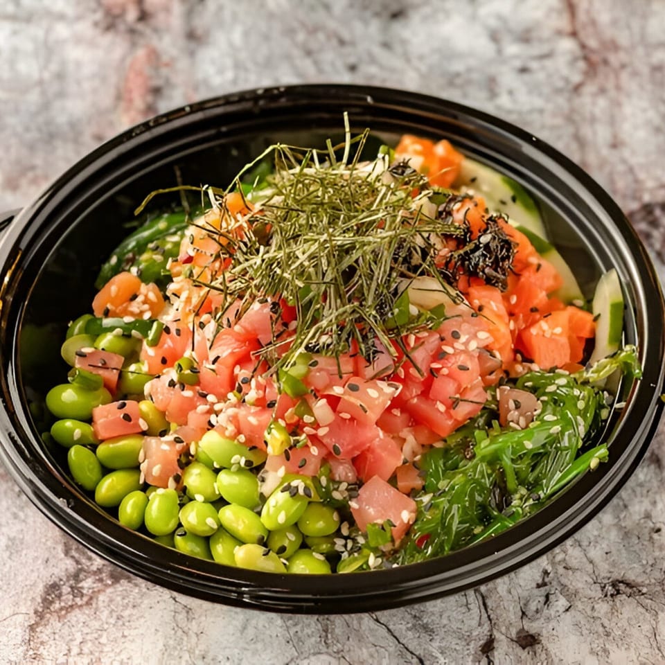A vibrant PokeCity poke bowl with salmon, edamame, seaweed, and cucumbers, topped with sesame seeds.