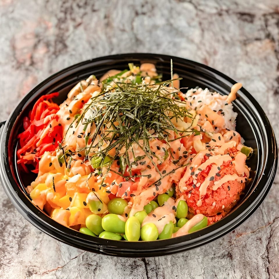 A vibrant PokeCity poke bowl with salmon, tuna, edamame, pineapple, and seaweed, drizzled with sauce.