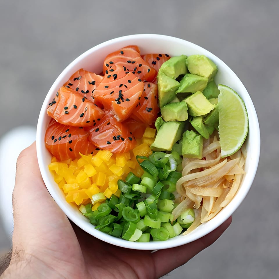 A hand holds a PokeCity poke bowl with salmon, avocado, yellow peppers, green onions, and pickled ginger.